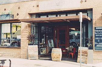 Exterior of Local 1205 Restaurant with Wooden Barrel and Menu Signs