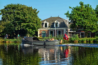 Boat with Red Flag Cruising on a Sunny Canal