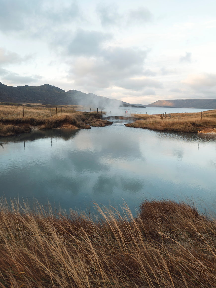 Serene Geothermal Landscape with Steaming Hot Springs and Mountains