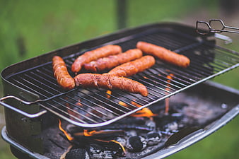Sausages grilling on charcoal barbecue outdoors