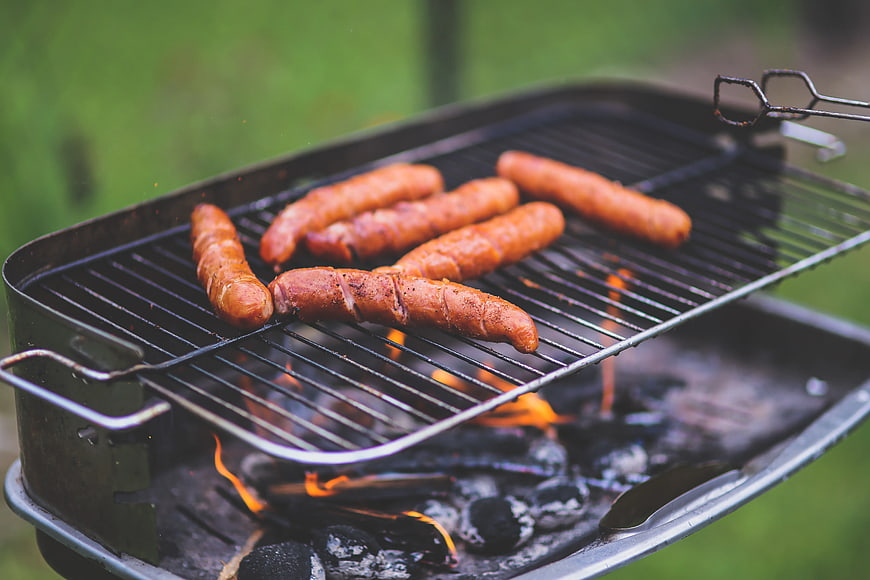 Sausages grilling on charcoal barbecue outdoors