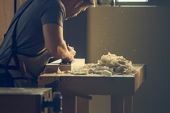 Carpenter Planing Wood with Hand Plane in Workshop