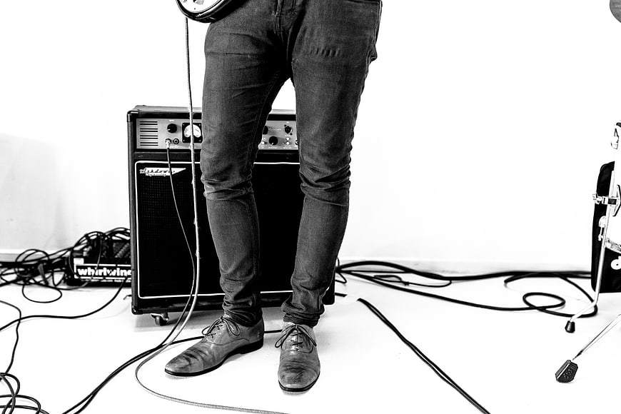 Musician legs with guitar amplifier and cables
