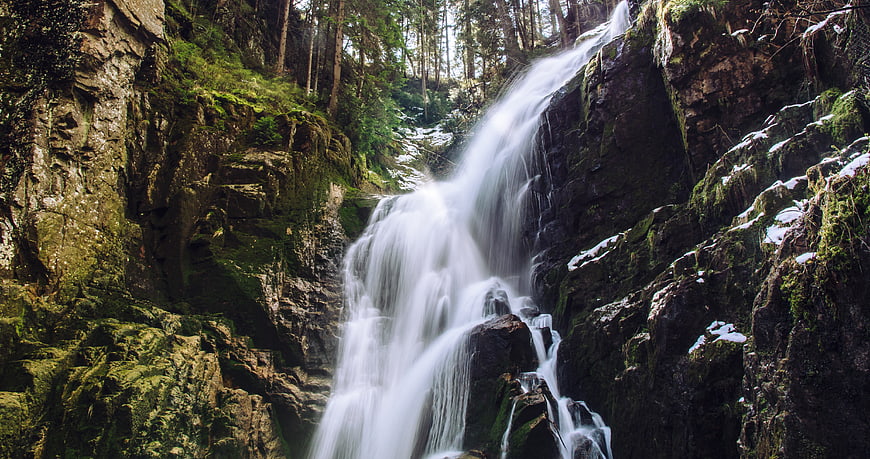 Majestic waterfall cascading down mossy rocks in a forest