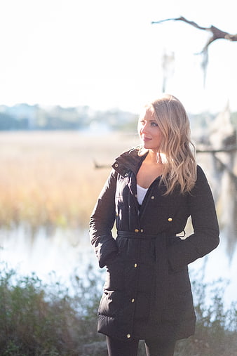 Blonde Woman in Black Coat Standing by Lake