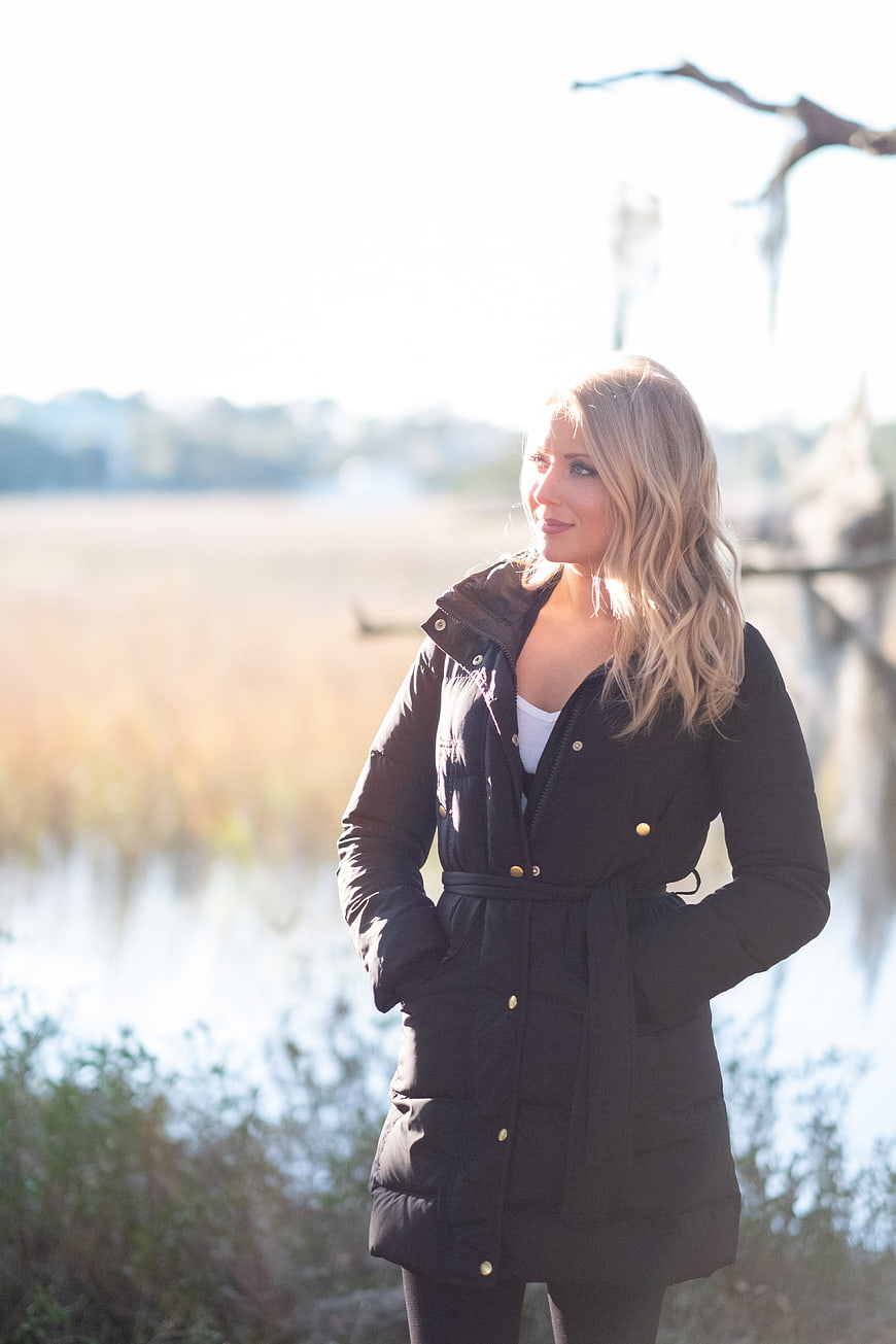 Blonde Woman in Black Coat Standing by Lake