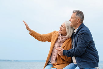 Happy Senior Couple Pointing at Horizon by the Sea