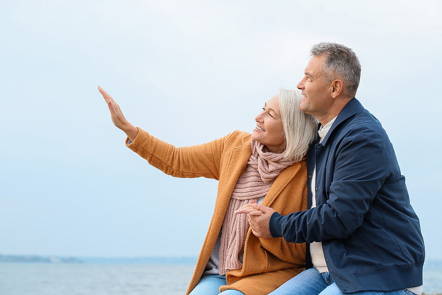 Happy Senior Couple Pointing at Horizon by the Sea