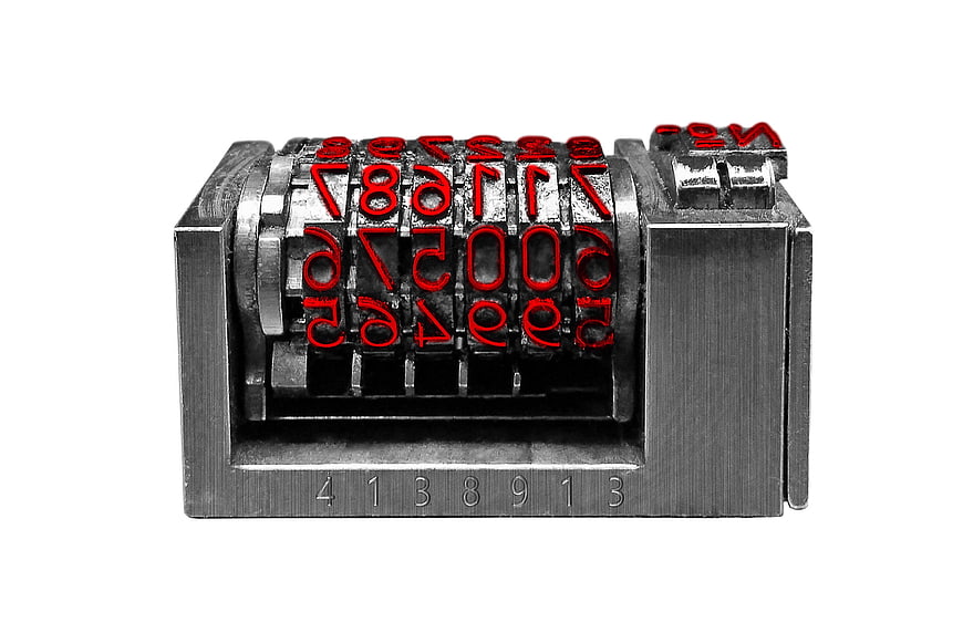 Vintage metal numbering machine with red digits on white background