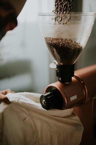 Coffee beans pouring into copper grinder hopper