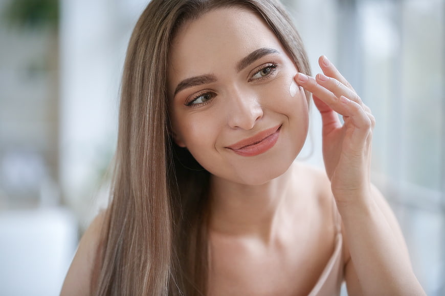 Woman applying skincare cream to face