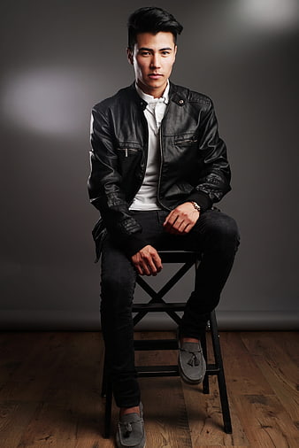 Handsome Asian man in leather jacket sitting on stool