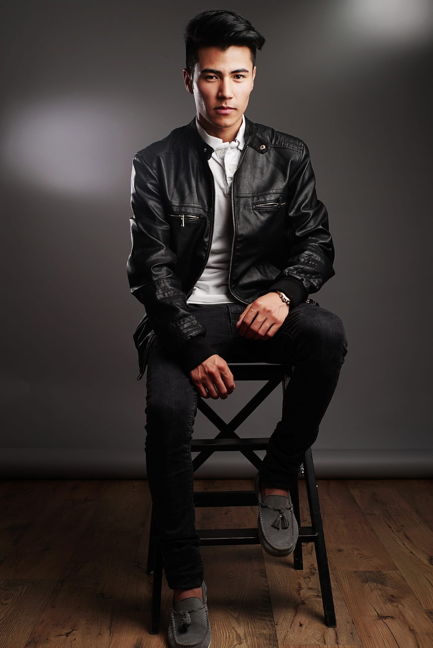 Handsome Asian man in leather jacket sitting on stool