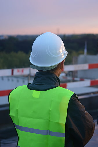 Construction Worker in Safety Vest and Helmet at Sunset