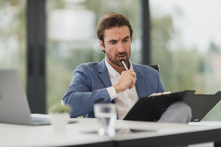 Thoughtful businessman reviewing documents in modern office