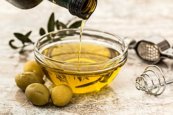 Pouring Olive Oil into Glass Bowl with Fresh Olives