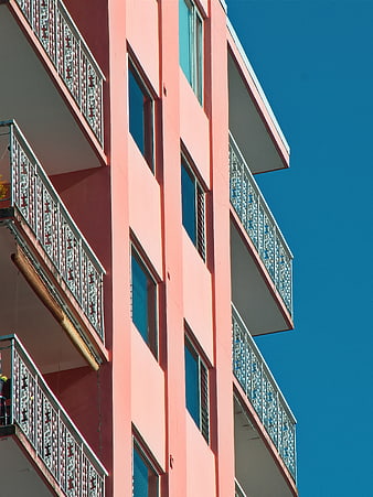 Pink Apartment Building with Balconies Against Blue Sky