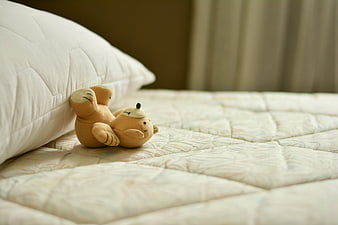 Cute stuffed animal lying on a soft white mattress