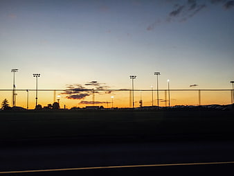 Silhouette of Stadium Lights Against Golden Sunset Sky