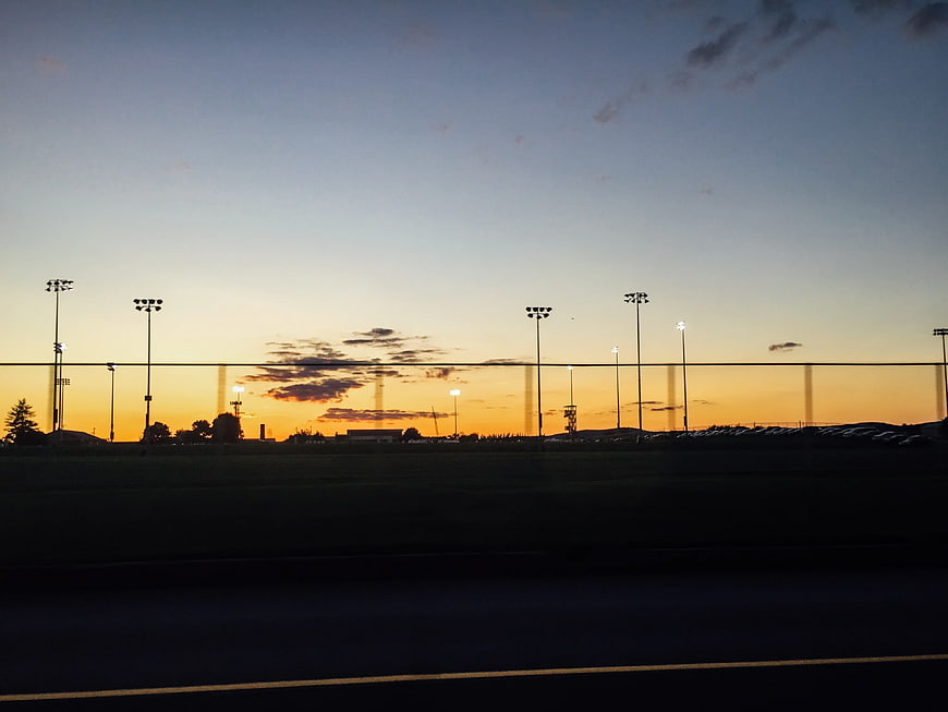 Silhouette of Stadium Lights Against Golden Sunset Sky