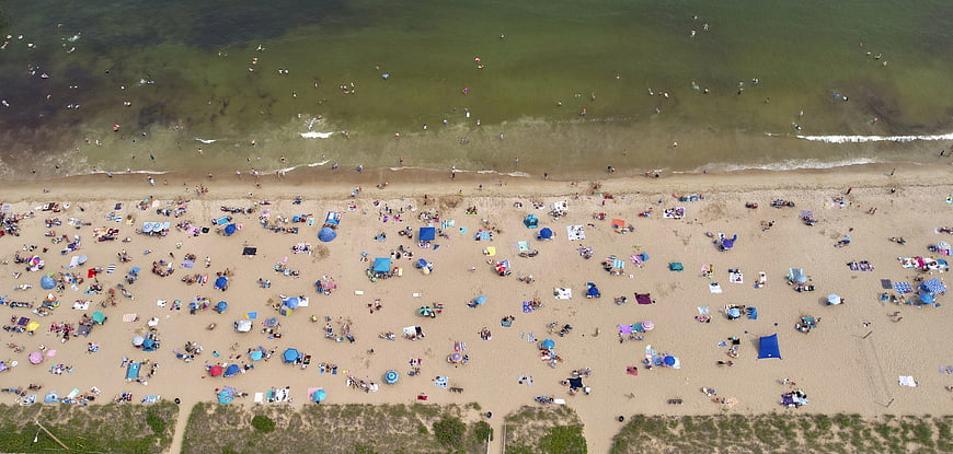 Aerial View of Crowded Beach with Colorful Umbrellas and Swimmers