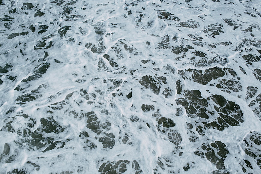 Aerial View of White Sea Foam on Dark Ocean Water