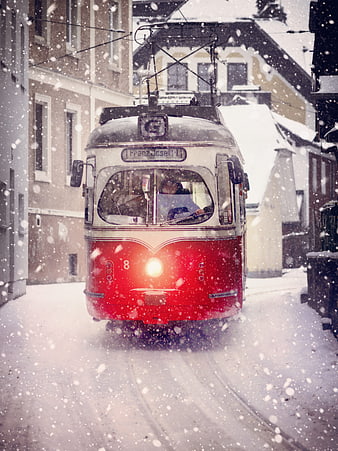 Vintage red tram driving through snowy city street
