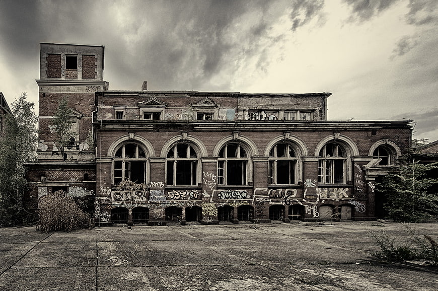 Abandoned brick factory building with graffiti and broken windows