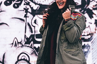 Laughing Woman in Green Jacket Against Graffiti Wall