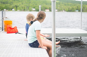Children sitting on dock splashing feet in lake