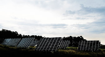 Solar panels in a field under a cloudy sky