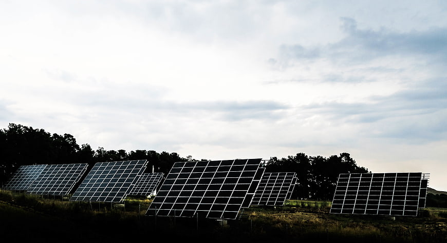 Solar panels in a field under a cloudy sky
