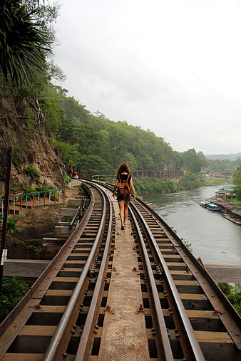 Woman Walking On Railway Tracks Near River In Thailand