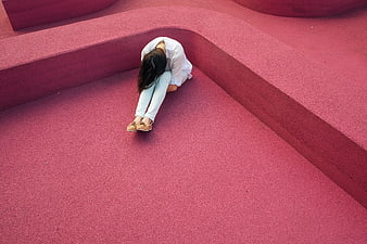 Woman sitting alone on pink curved steps looking down
