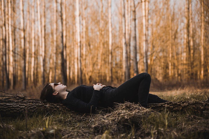 Woman Lying on Log in Golden Autumn Forest