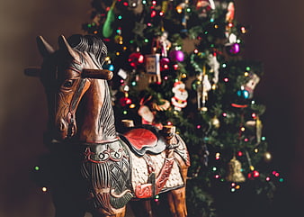 Wooden Horse Figurine in Front of Christmas Tree