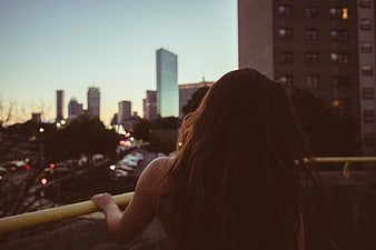 Woman looking at city skyline at dusk from bridge