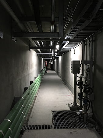Underground industrial utility corridor with green pipes and valves