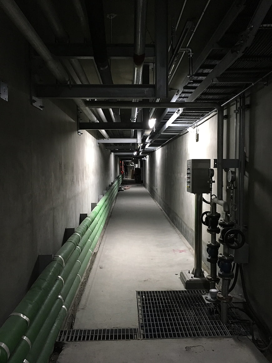 Underground industrial utility corridor with green pipes and valves