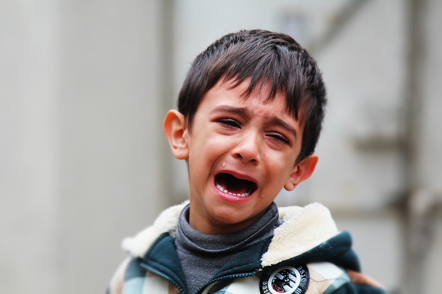 Close-up portrait of a crying young boy with tears