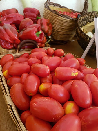 Fresh red tomatoes and peppers in wicker baskets at market