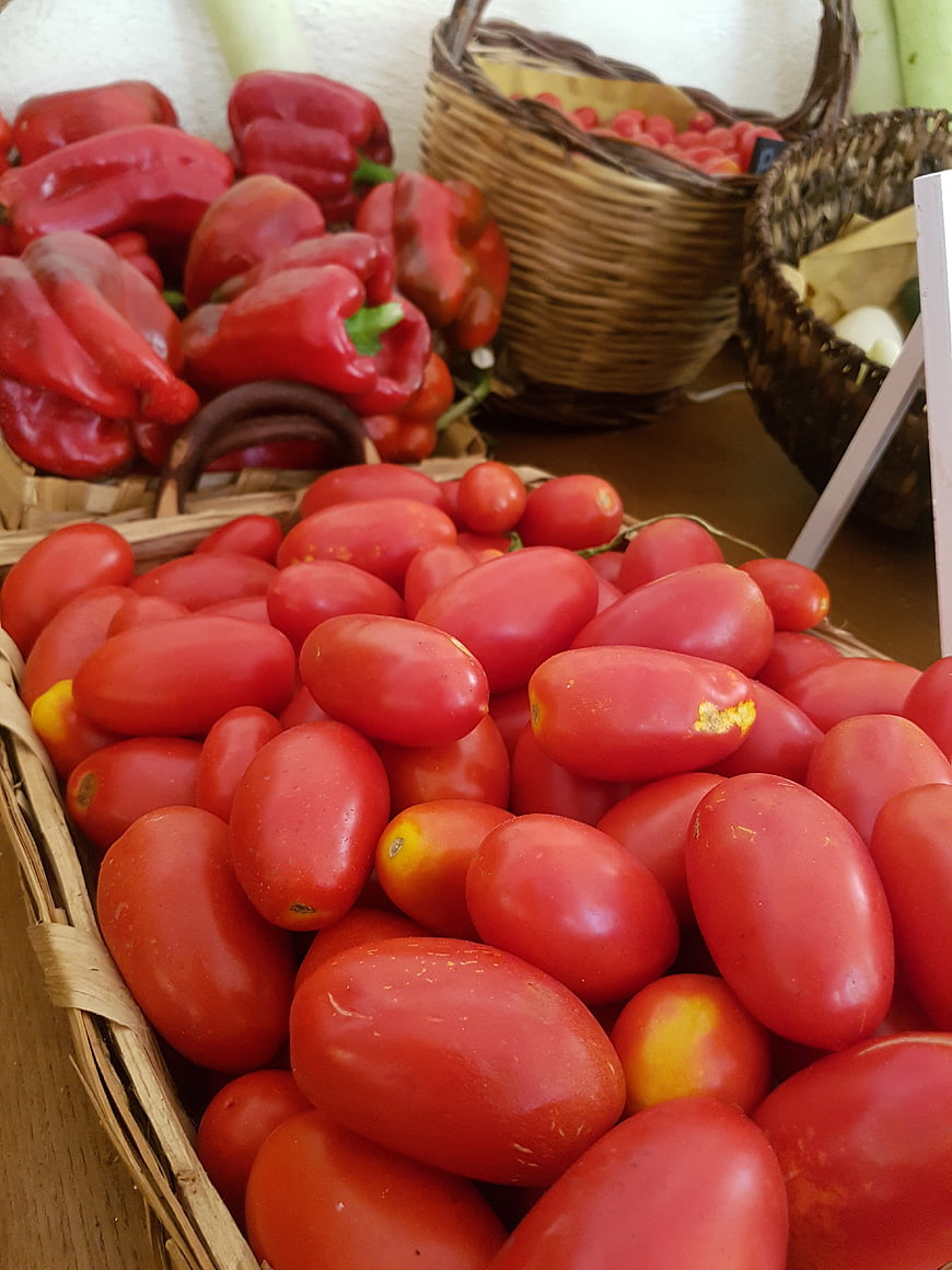 Fresh red tomatoes and peppers in wicker baskets at market