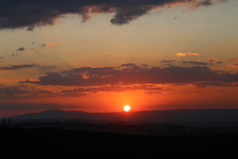 Vibrant orange sunset over silhouetted mountains and city