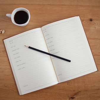 Open notebook with pencil and coffee on wooden desk
