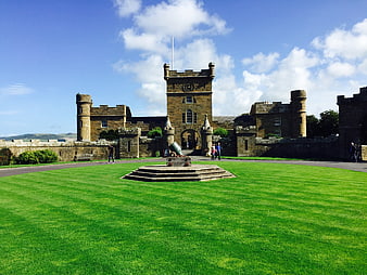 Historic stone castle with green lawn and cannon