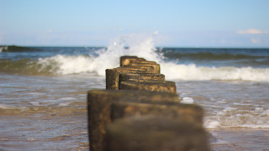 Wooden Groynes on Beach with Crashing Waves