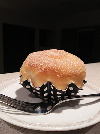 Sugar-coated bun in polka dot wrapper on white plate