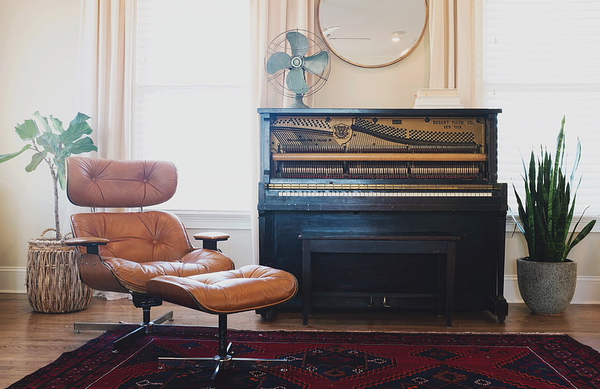 Vintage upright piano and leather lounge chair in cozy living room