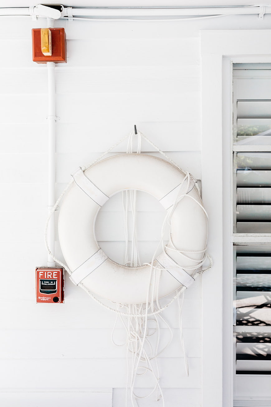 White life preserver ring on white wall with fire alarm