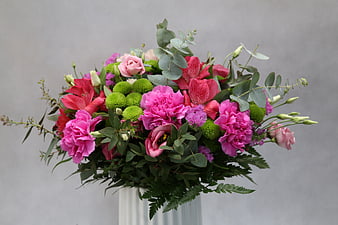 Colorful floral arrangement in a white vase against a gray background